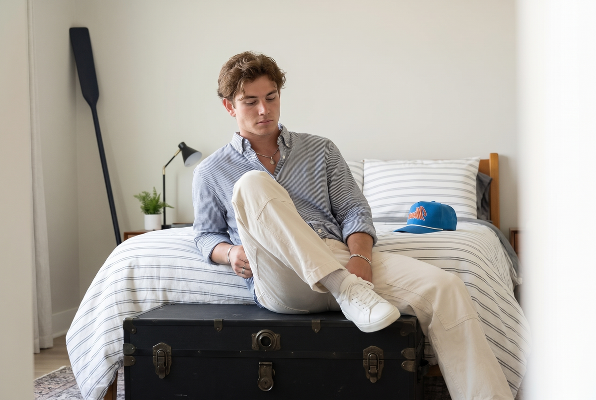 Man relaxing in a bright bedroom in a striped shirt